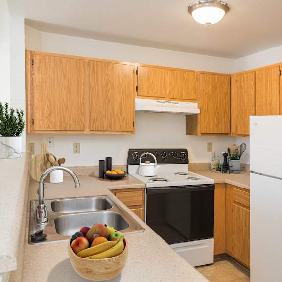 a kitchen with wooden cabinets and a bowl of fruit on the counter.