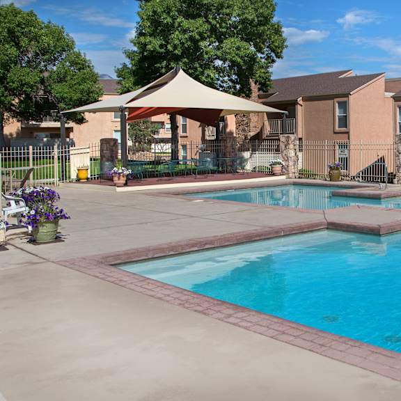 a swimming pool surrounded by a patio and a gazebo.