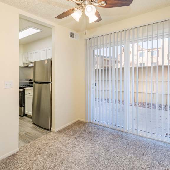 a room with a fan and a sliding door leading to a balcony.