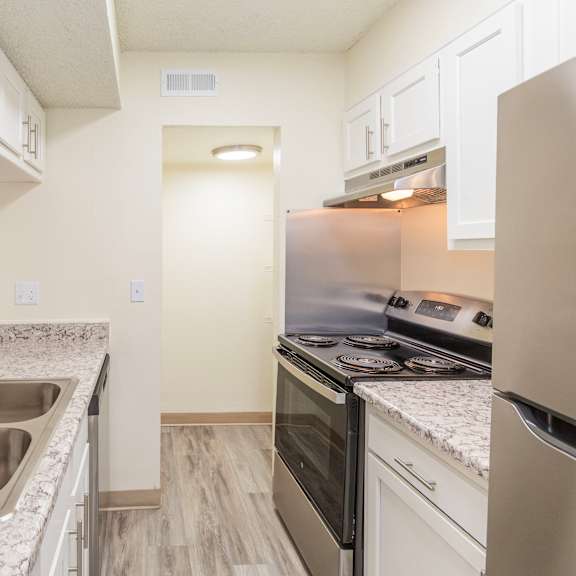 a kitchen with a stainless steel sink and white cabinets.