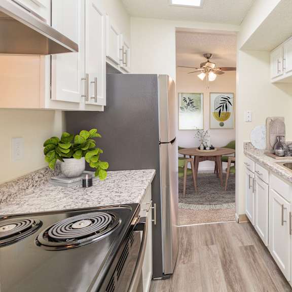 a kitchen with a stove, sink, and refrigerator.