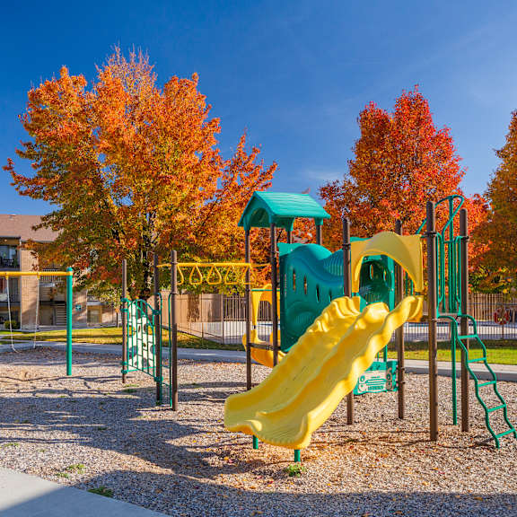 a playground with a yellow slide and green play structure.