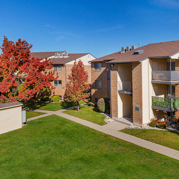 apartment complex with a green lawn and trees with red leaves.