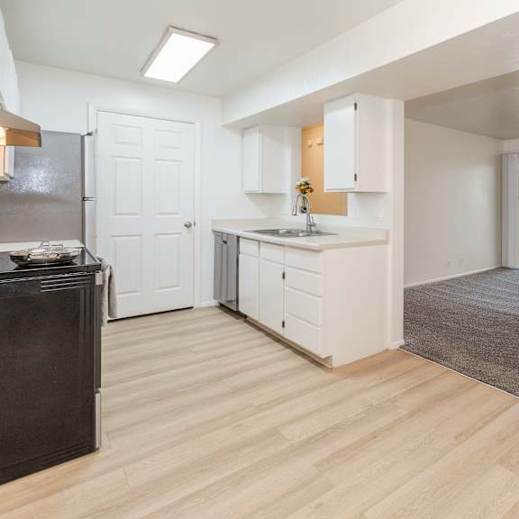 a kitchen with white cabinets and a black fridge.