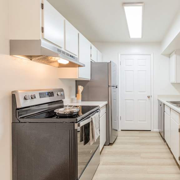 a kitchen with a black stove top oven and white cabinets.