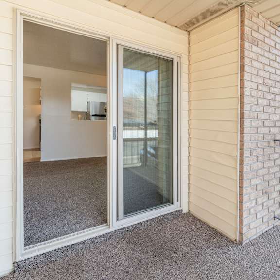 a patio area with a glass door and a brick wall.