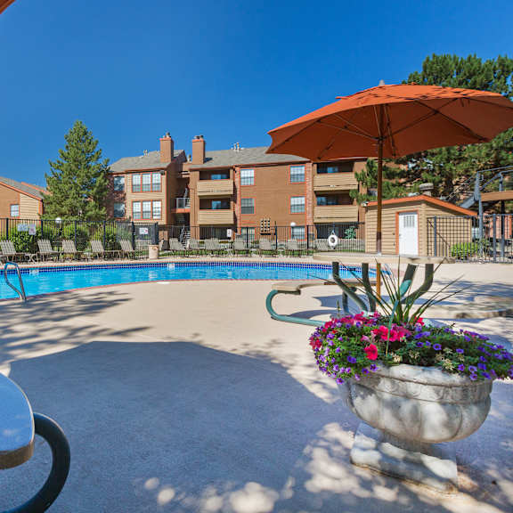 a pool area with a table and chairs and umbrellas.