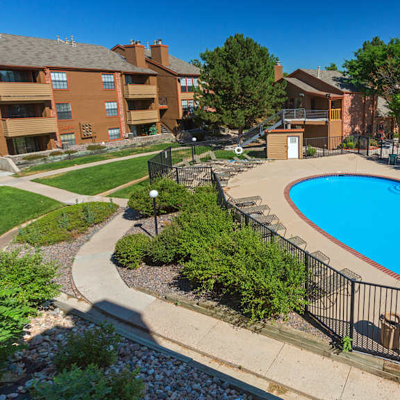 a swimming pool surrounded by a black fence and a building in the background.