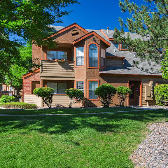 a house with a brown roof and a tree in front.