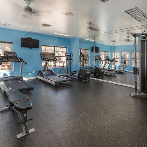 a spacious gym with treadmills, elliptical machines, and weightlifting equipment.