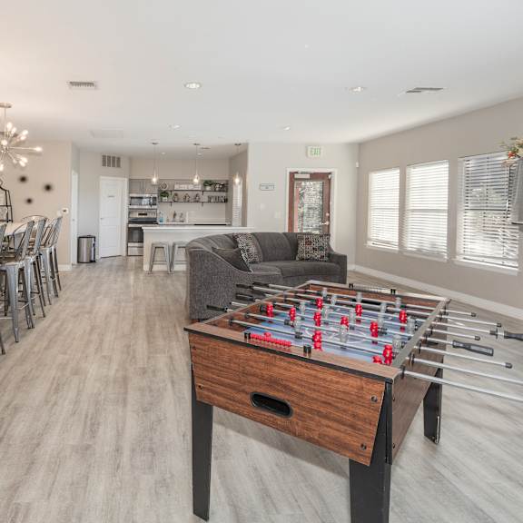 a foosball table is in the middle of a room with a bar and dining area.