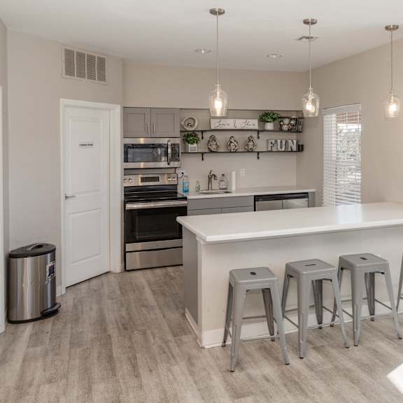 a kitchen with a white counter and grey stools.