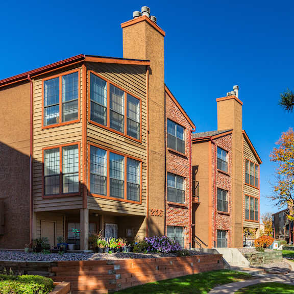 a row of red brick apartment buildings with trees in the background.