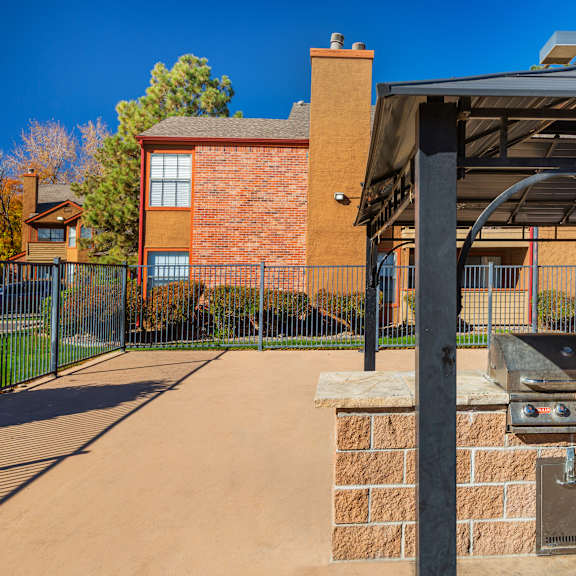 a barbecue grill is on a brick pillar under a black awning.