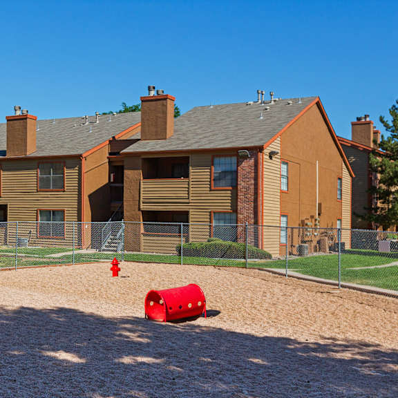 a red barrel sits in the sand in front of a building.