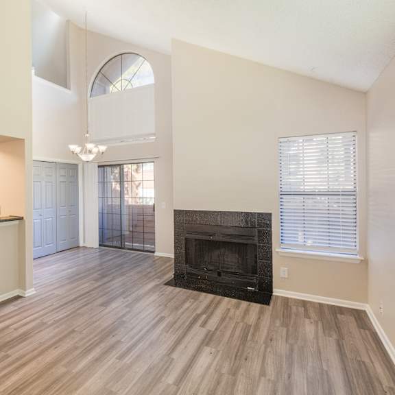 a living room with a fireplace and a kitchen area in the background.