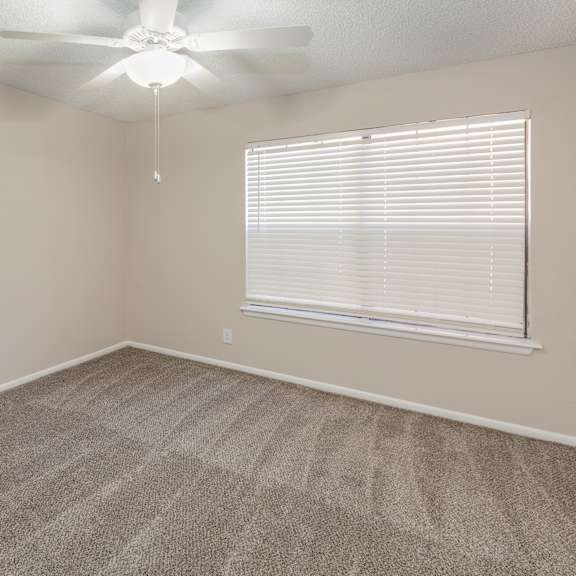 a room with a ceiling fan and a window with blinds.