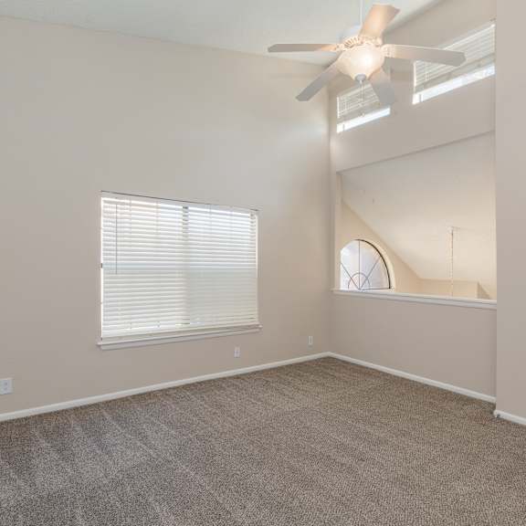 a room with a ceiling fan and carpeted floor.