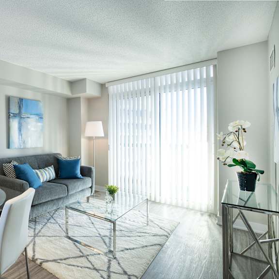 a modern living room with a glass dining table and white chairs.