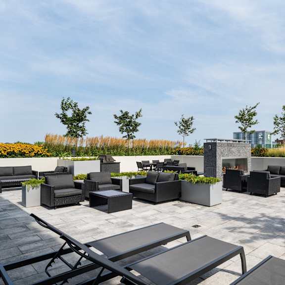 a rooftop patio with tables and chairs and a fire pit