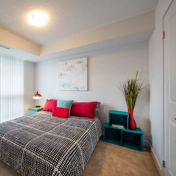 a bedroom with a bed, pillows, and a plant.