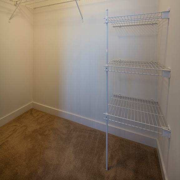 empty white shelving unit in a room with brown carpet.
