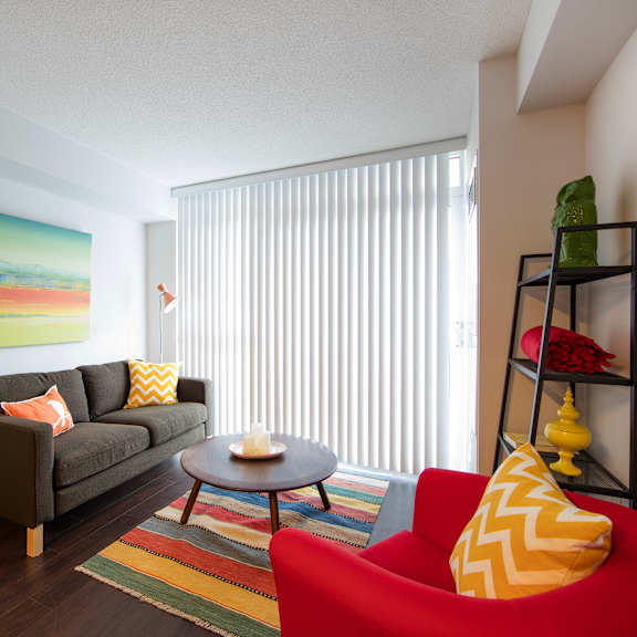 a living room with a red chair and a painting on the wall.