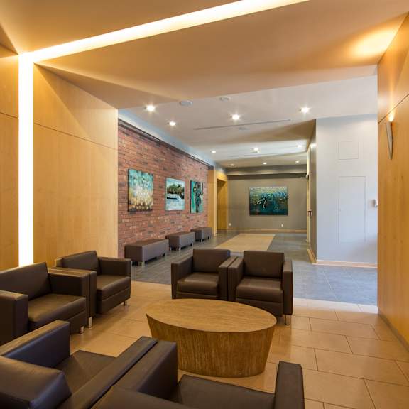 a modern waiting room with leather chairs and a brick wall.