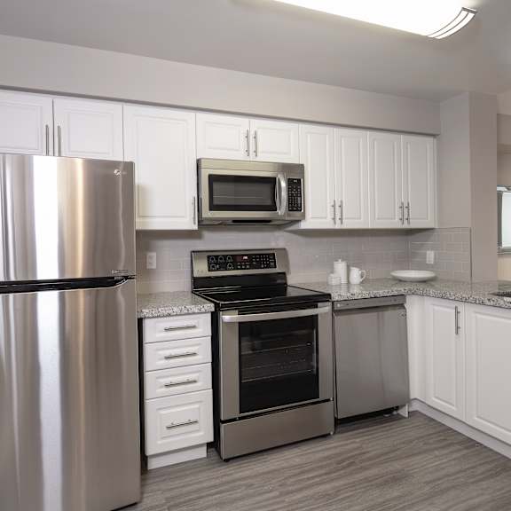 a modern kitchen with stainless steel appliances and white cabinets.