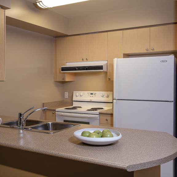a kitchen with a white refrigerator, sink, and stove.