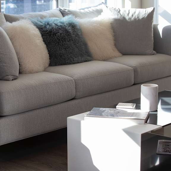 a grey couch with pillows and a blanket on it.