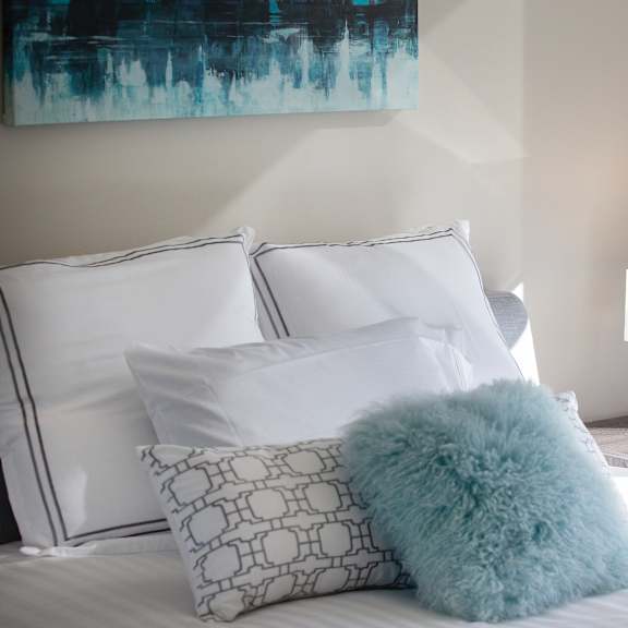 a bed with white pillows and a blue fluffy pillow on it.