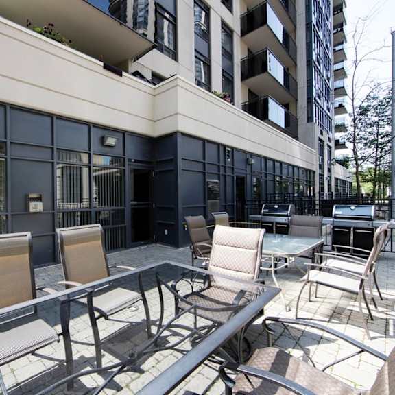 a patio with chairs and tables in front of a building