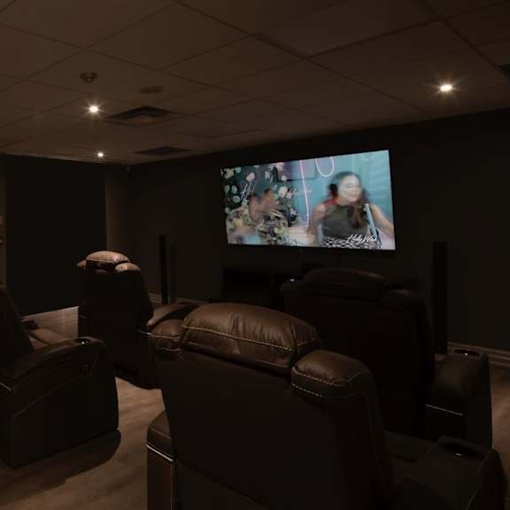 a home cinema room with leather chairs and a flat screen tv