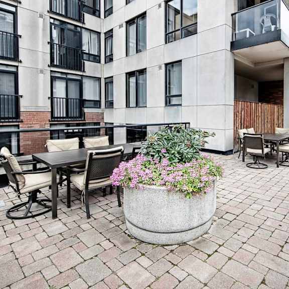 a patio with a grill and tables and chairs