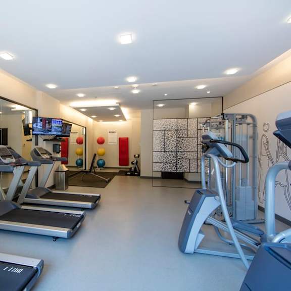 a gym with cardio equipment and a flat screen tv