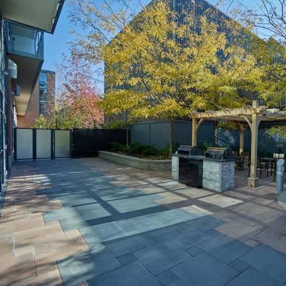 a patio with a fire pit and a pergola in front of a building