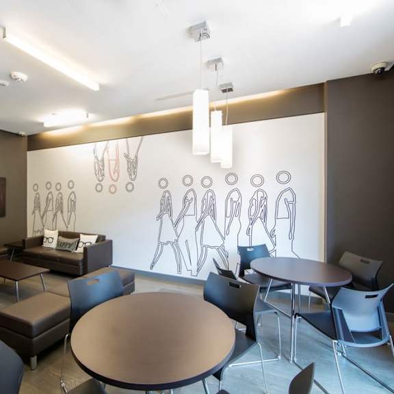 a room with tables and chairs and a mural on the wall