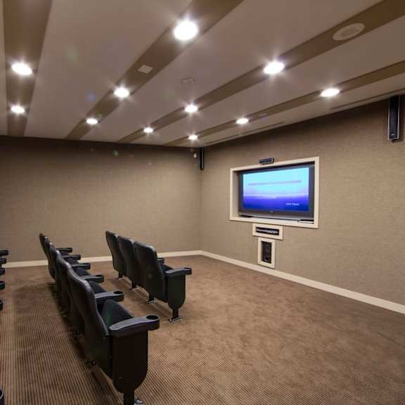 a large room with a large screen tv on the wall and a row of black chairs