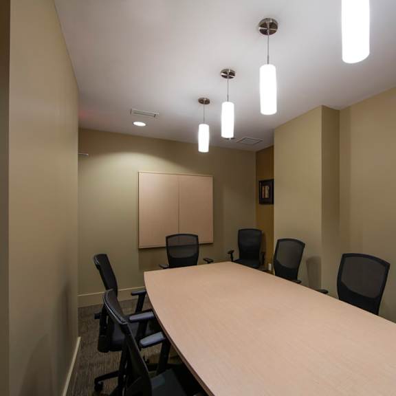 a small conference room with a long table and black chairs