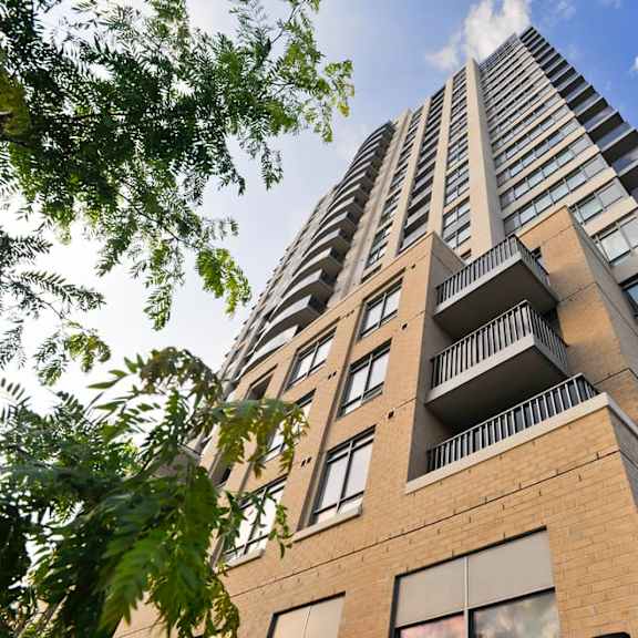 looking up at a tall apartment building with a blue sky in the background