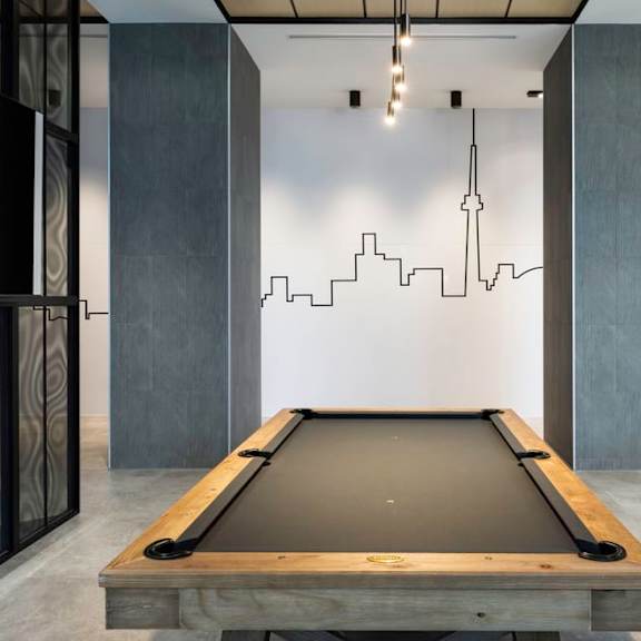 a pool table sits in the middle of a room with a cityscape painted on the wall