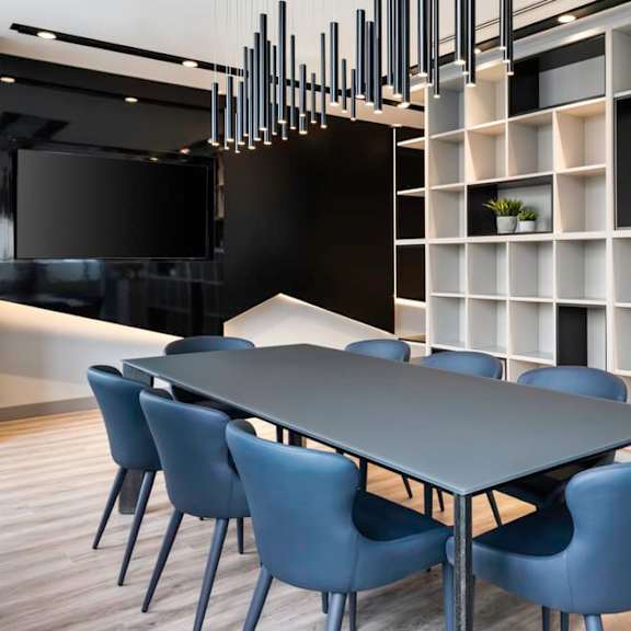 a long black table with blue chairs in front of a white bookshelf