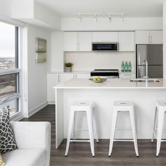 a white kitchen with white stools and a stainless steel refrigerator