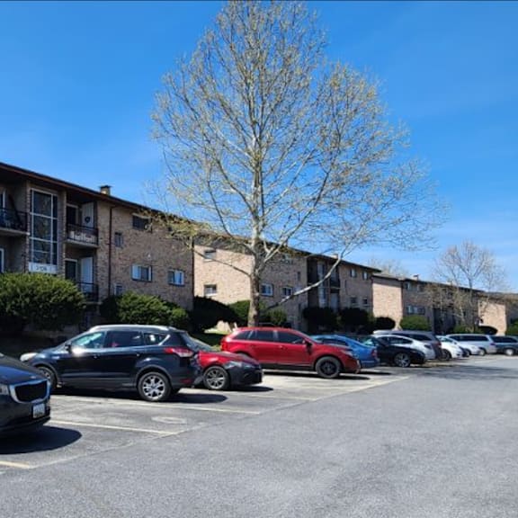 a parking lot with cars and apartment buildings in the background.