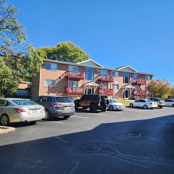 cars parked in front of a multi-story apartment building.