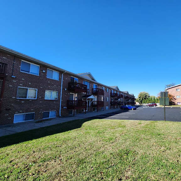 a sunny day at a residential area with apartment buildings and a parking lot.