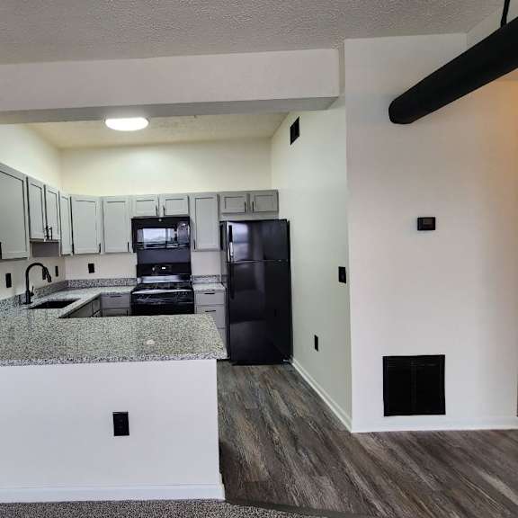 a kitchen with granite countertops and a black refrigerator.