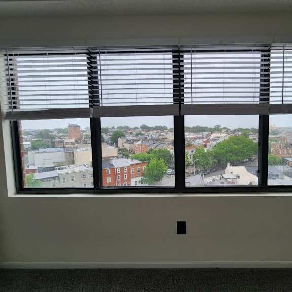 a window with blinds overlooking a cityscape.