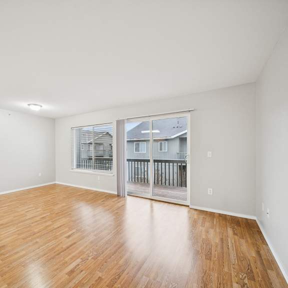 a room with wooden flooring and a window overlooking a balcony.